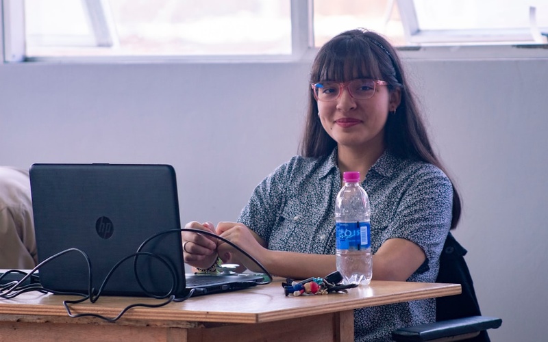 Female computer science student working on AI project with multiple screens showing code and neural networks